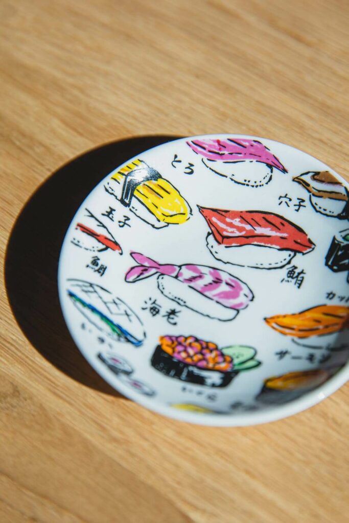 A modern rendition of Japanese ceramics, a colorful plate decorated with paintings of sushi.