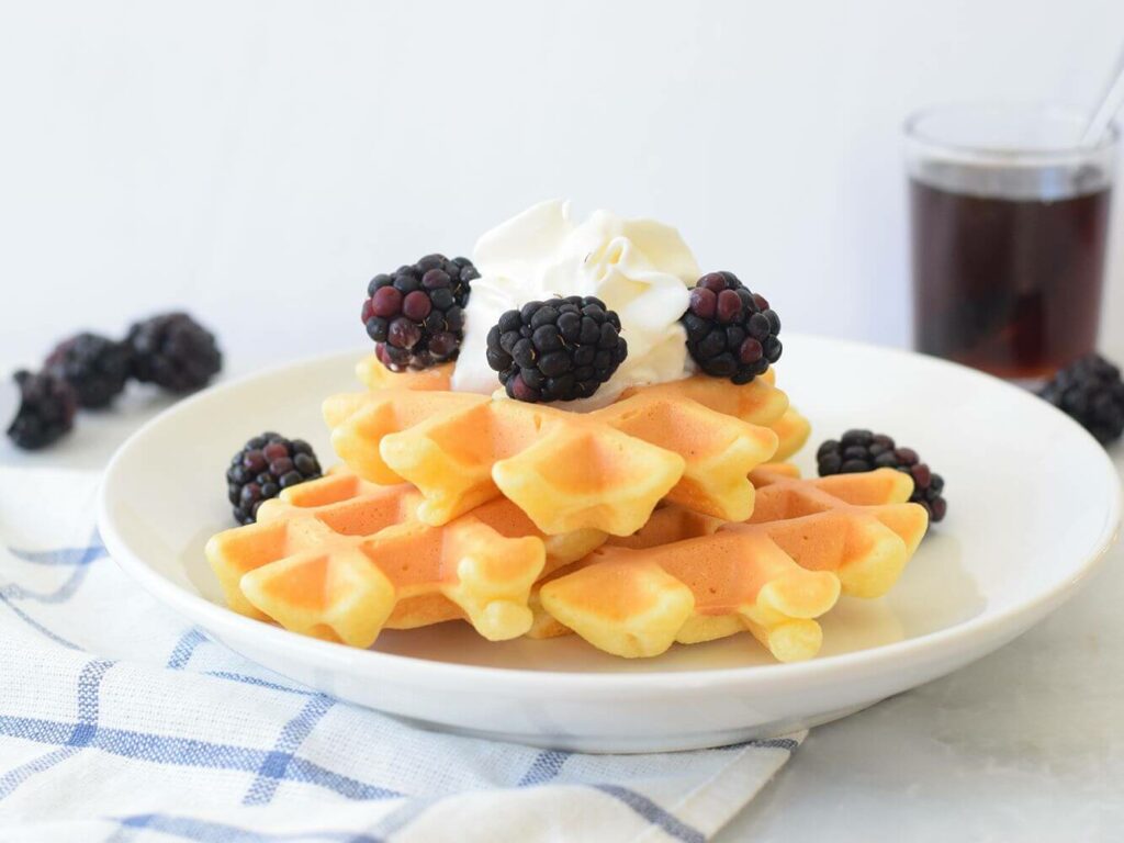 A plate of Japanese waffles with seasonal fruit and whipped cream.