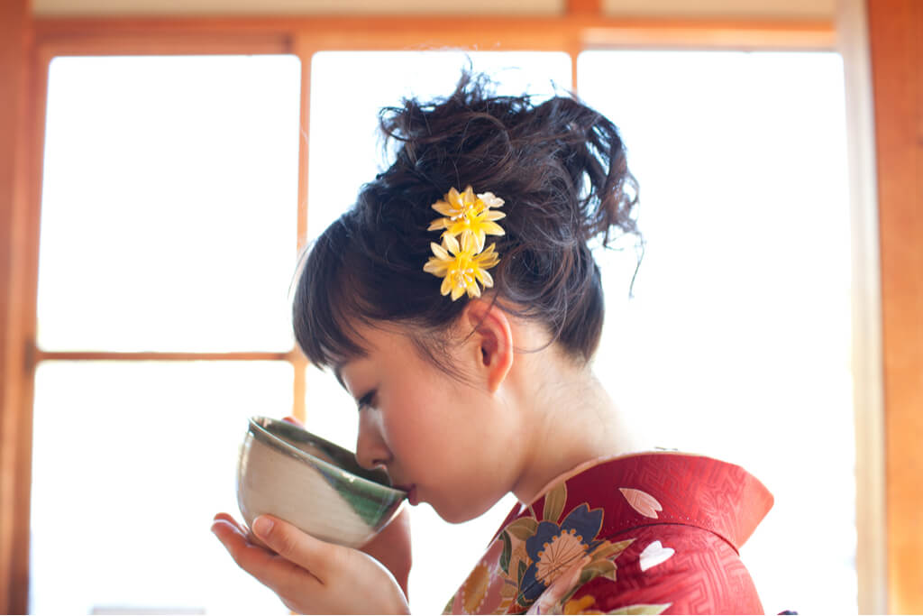 A woman sipping tea at a Japanese tea ceremony.