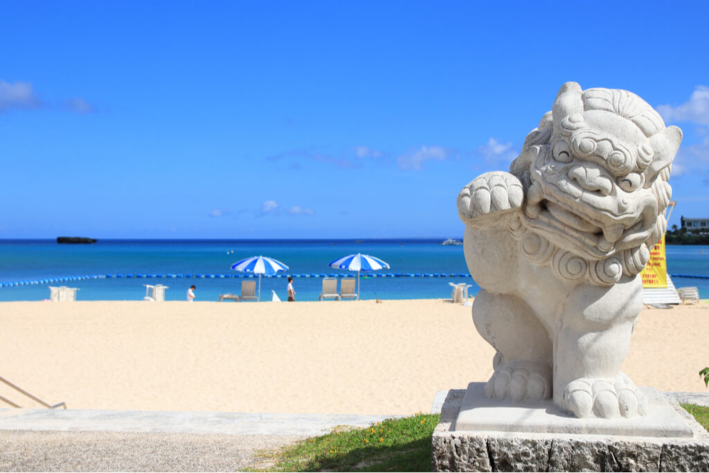 A Japanese guadian statue in front of a beautiful beach.