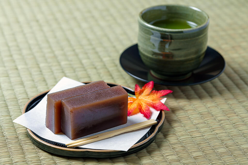 Red bean yokan on a plate next to a cup of green tea