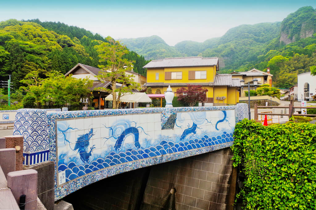 A porcelain bridge in Imari where Imari ware is made, with houses and mountains with trees in the background