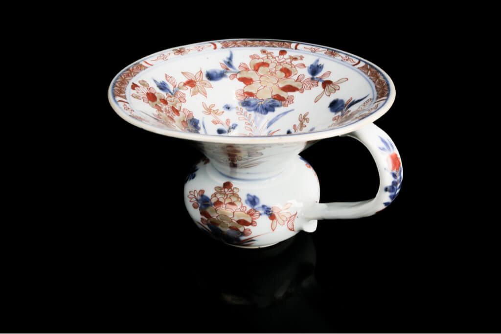 A Chinese Imari porcelain vase with gold, red, and blue flowers sitting on a black background