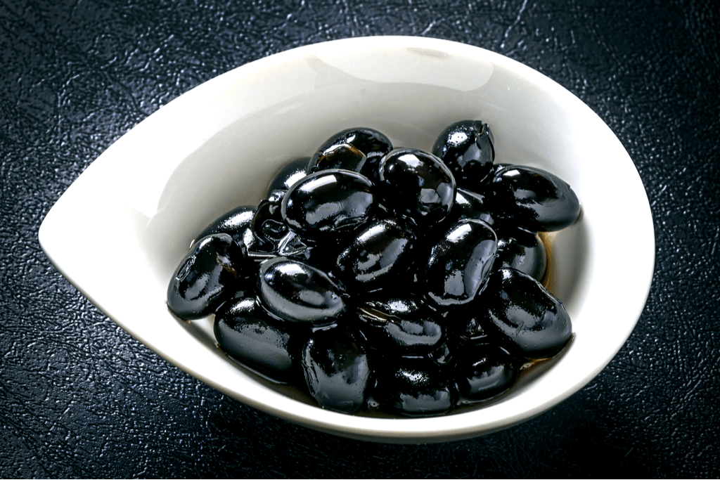 A bowl of large, shiny black beans, also known as kuromame.