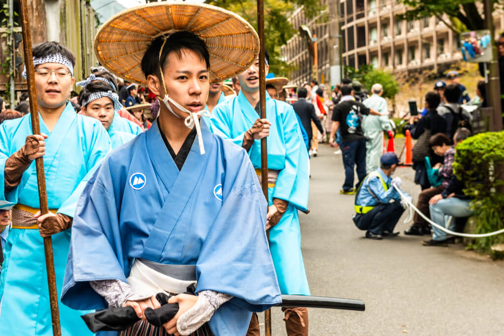 A man wearing a traditional Japanese garb at a feudal march festival in front of Hakone Yumoto onsen, a popular Hakone onsen area