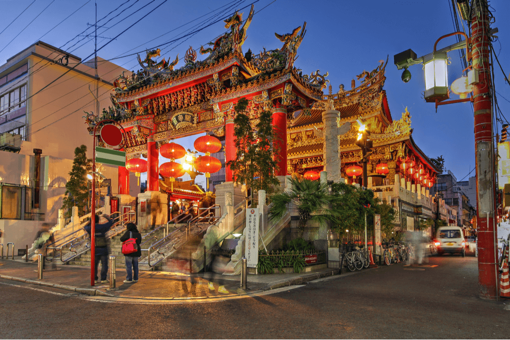 Two people standing and taking pictures of Kuan Ti Miao, a temple in Yokohama Chinatown.