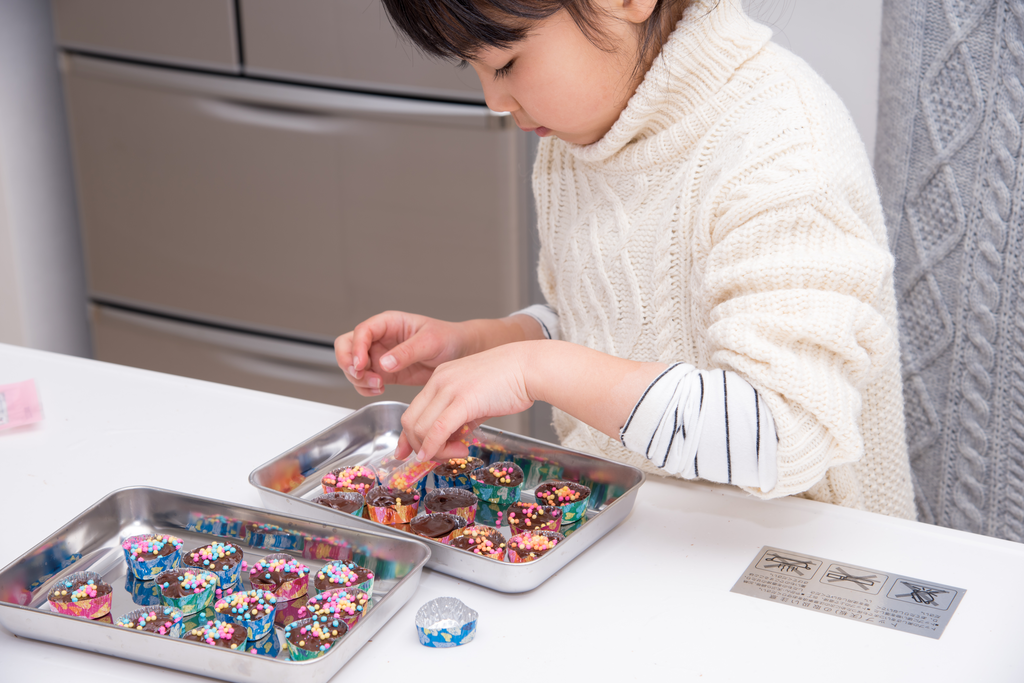 A little girl arranging chocolate.