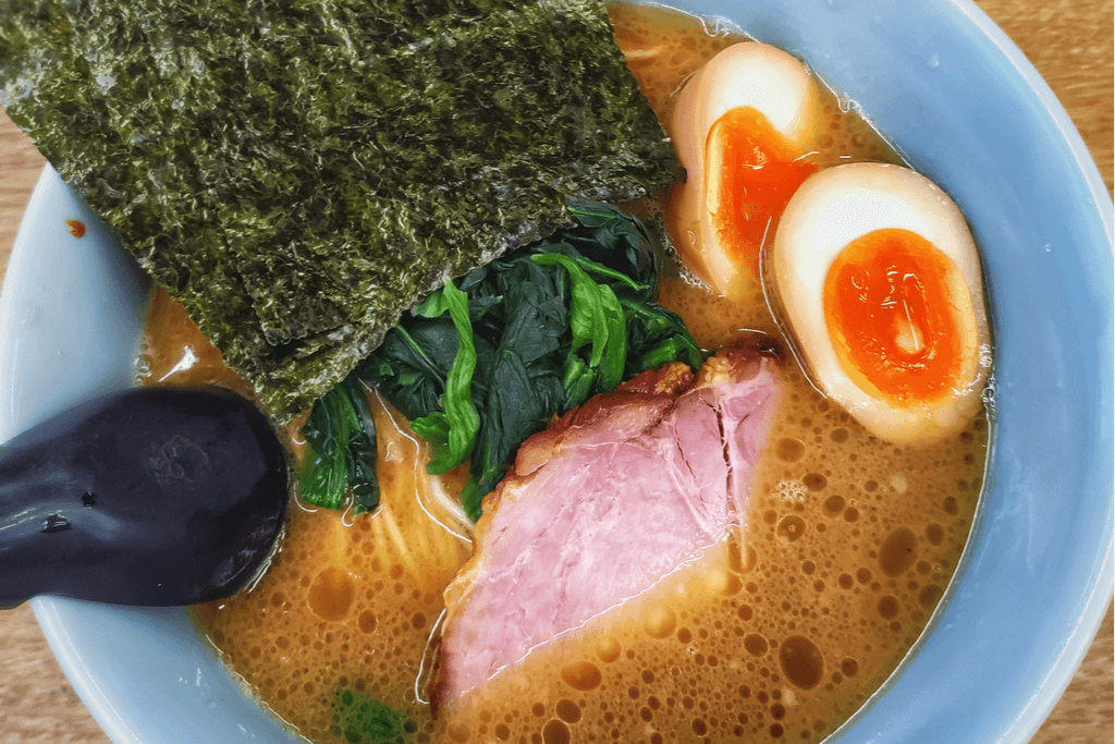 A bowl of Yokohama ramen with pork, spinach, eggs, and seaweed as toppings.
