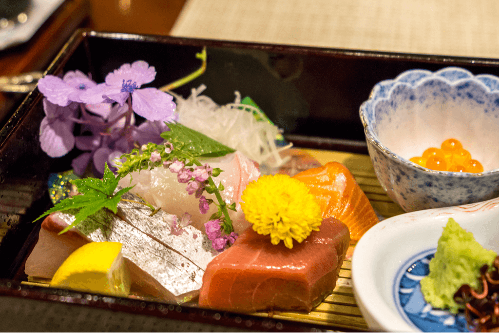 A tray of luxury sushi at one of the traditional Japanese inns that the Seven Stars in Kyushu stops at, with fish like salmon, salmon roe, and tuna on the plate.