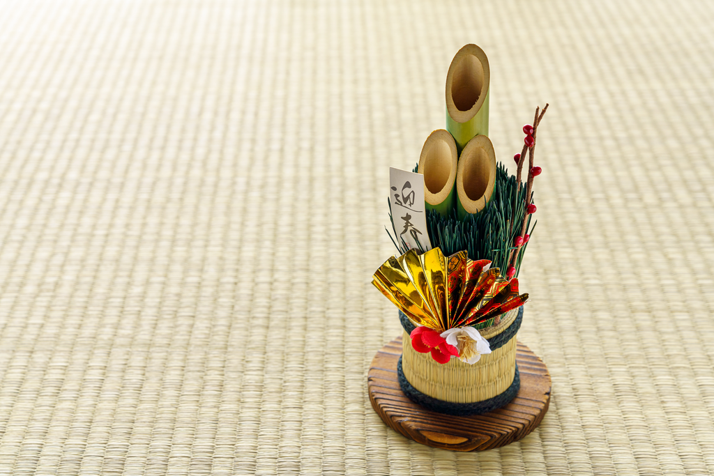 Decorative, hollowed-out bamboo with a foil fan on top of a  light green tatami mat.
