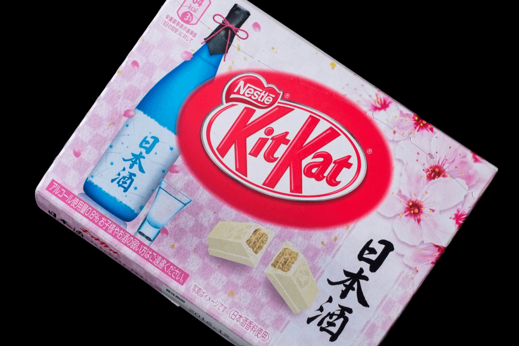A box of Japanese sake-flavored kit kats with a bottle of Japanese sake and many cherry blossoms on the box design. 