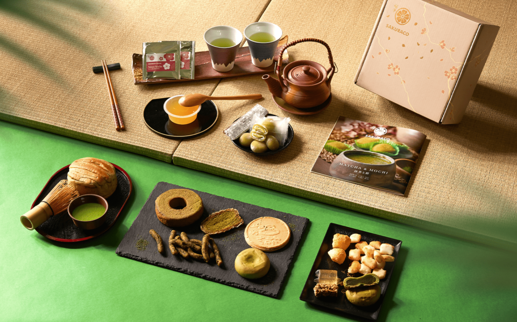 A shot of Sakuraco's Matcha Mochi box on a tatami mat.  There's an assortemnt of matcha tea and snacks. It has a much more traditonal vibe than Bokksu.