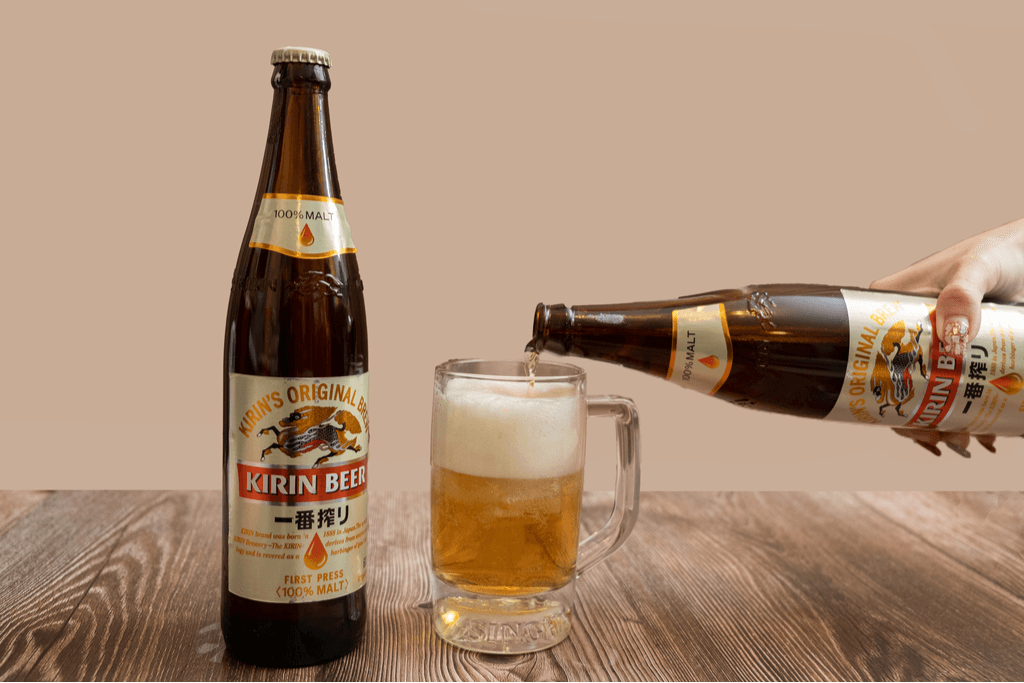 A bottle of Kirin, originally from Yokohama, sits next to a mug with a hand pouring beer from a second bottle into the mug.