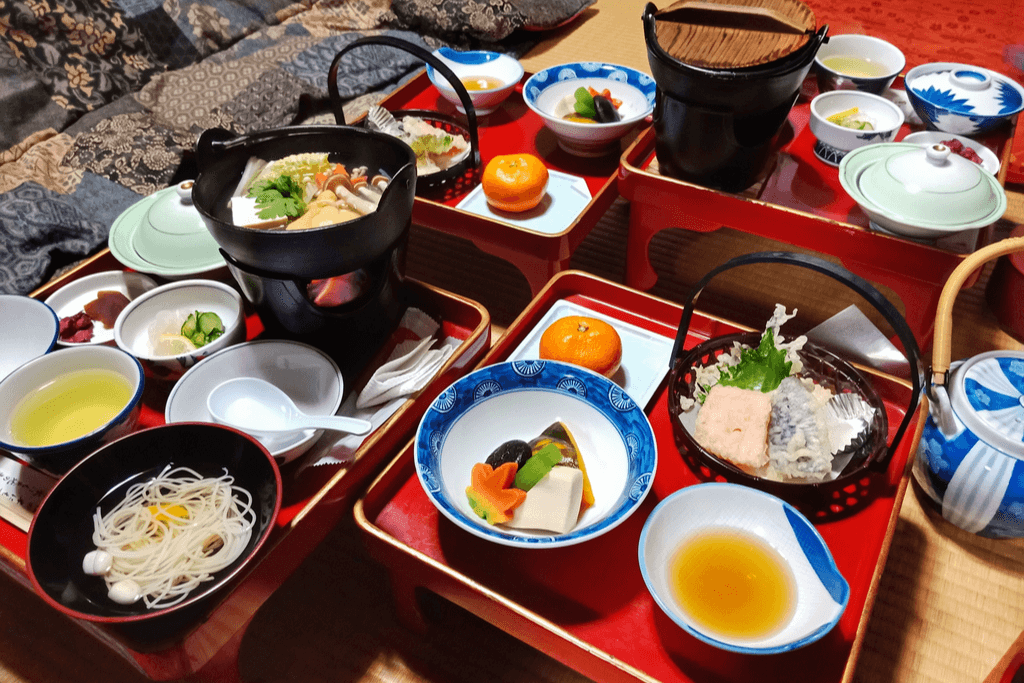 Trays of Shojin Ryori, vegetarian Kyoto foods, on many individual plates with hot pots full of vegetables on the trays.
