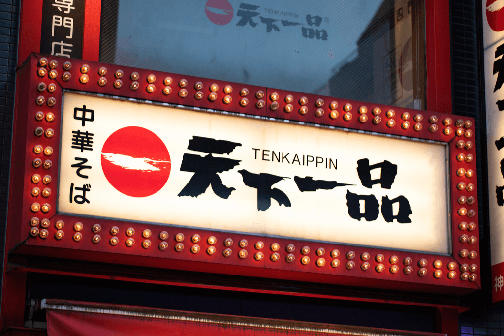 The signboard of Tenkaippin, a Kyoto ramen chain started in the city, with many flashing lights around it.