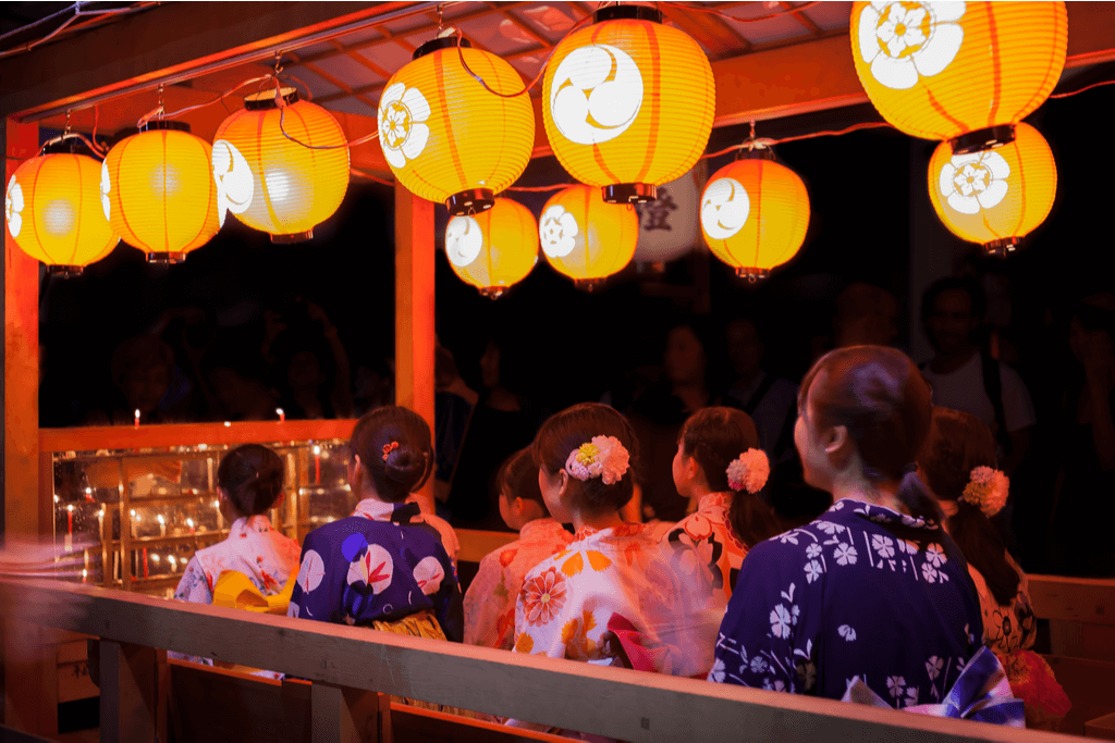 Women in Kimono sing at one of the night events of the Gion festival with many beautiful lanterns above them.