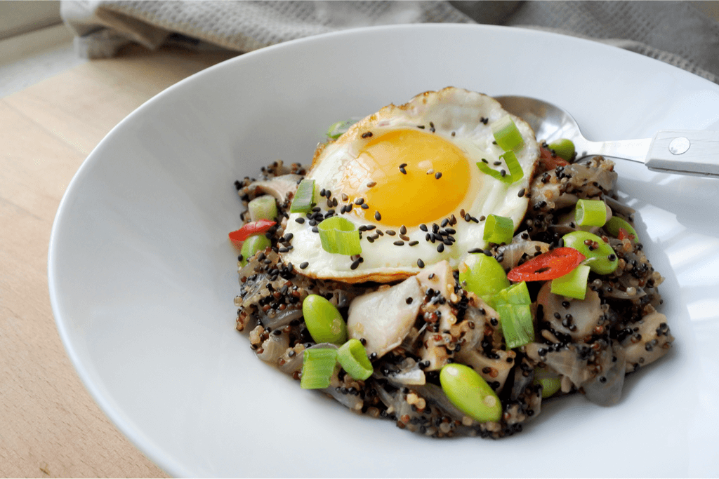 Black sesame seeds on top of fried rice with egg with a lot of meat and vegetables.