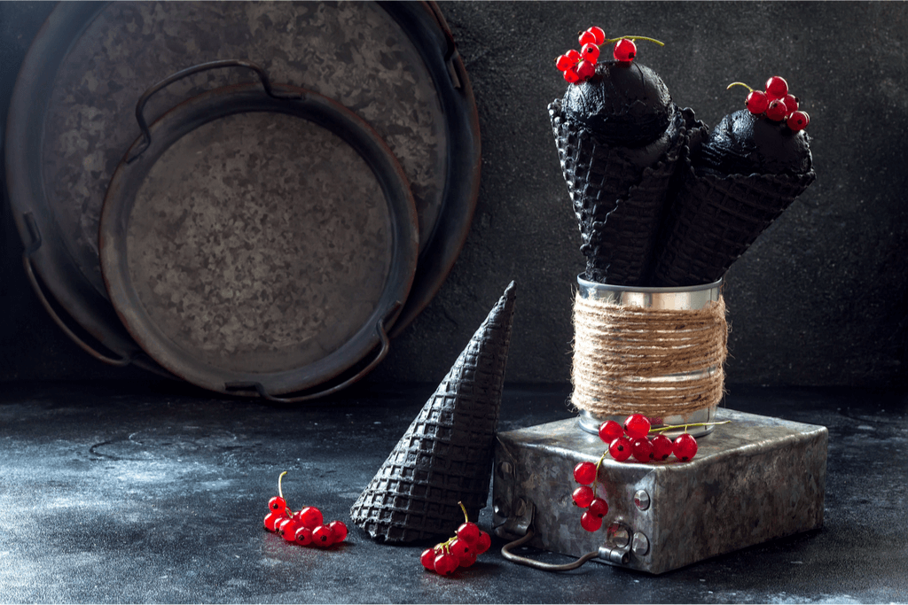 Black sesame ice cream in matching black waffle cones and topped with plastic cranberries.