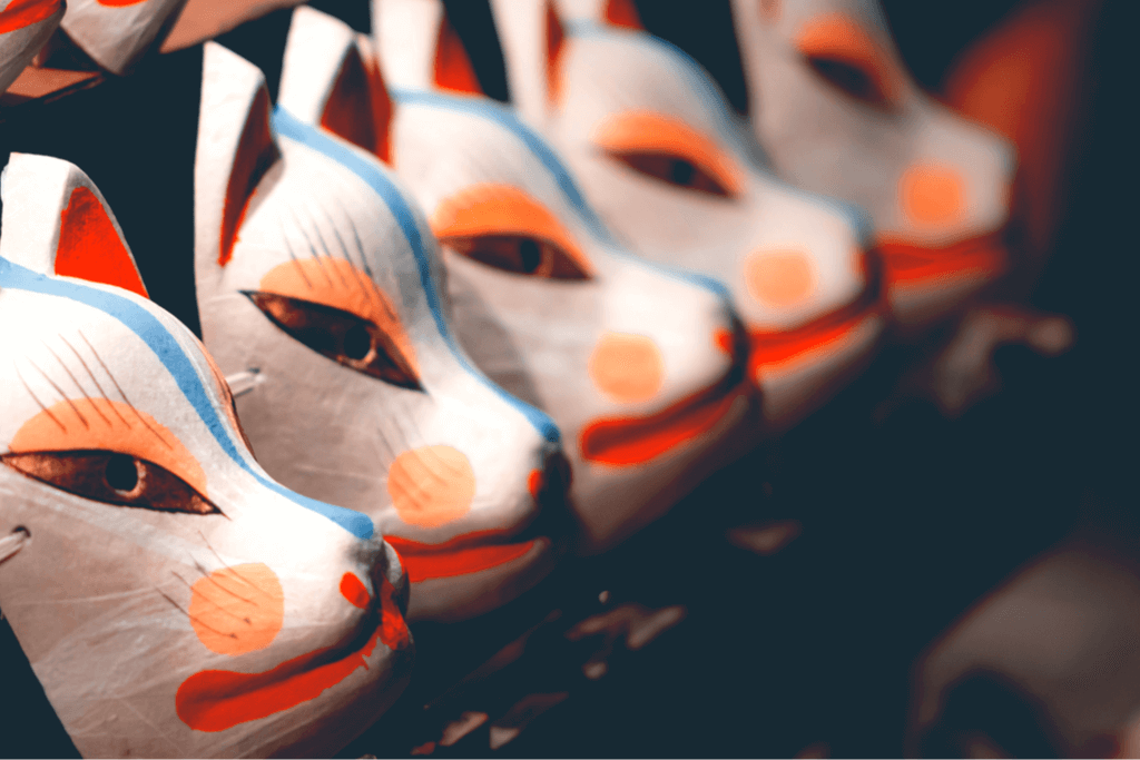 An image of kitsune (fox) masks, lined up all in a row.
