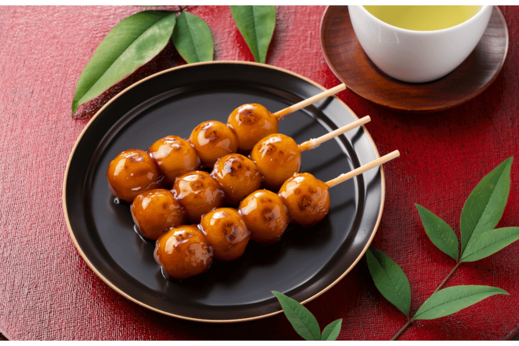 A photograph of mitarashi dango, one of many Kyoto sweets made of skewered mochi dumplings and covered with sweet soy sauce.