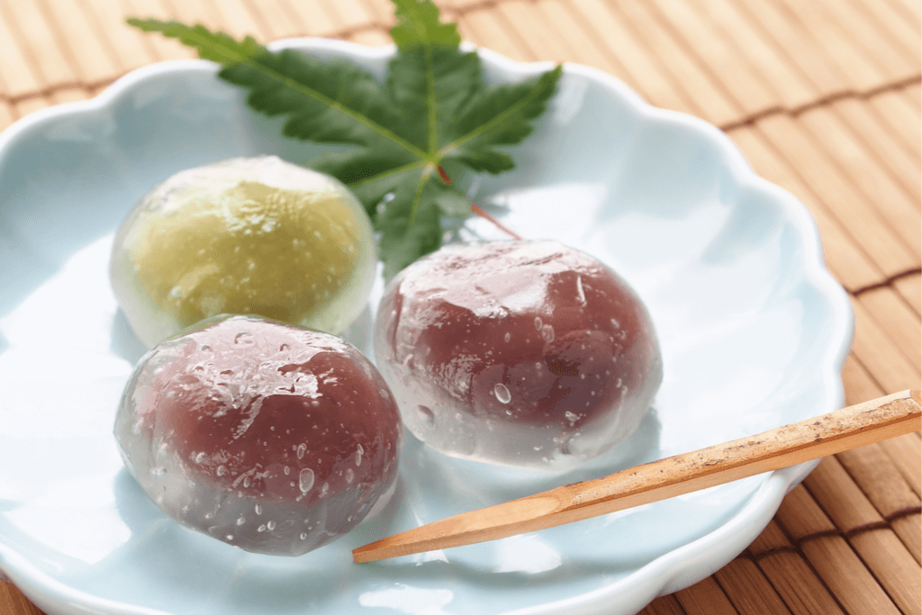 A photograph of mizu manjum which is a dessert  made of kuzu starch and stuffed with red bean paste and looks like huge water droplets.