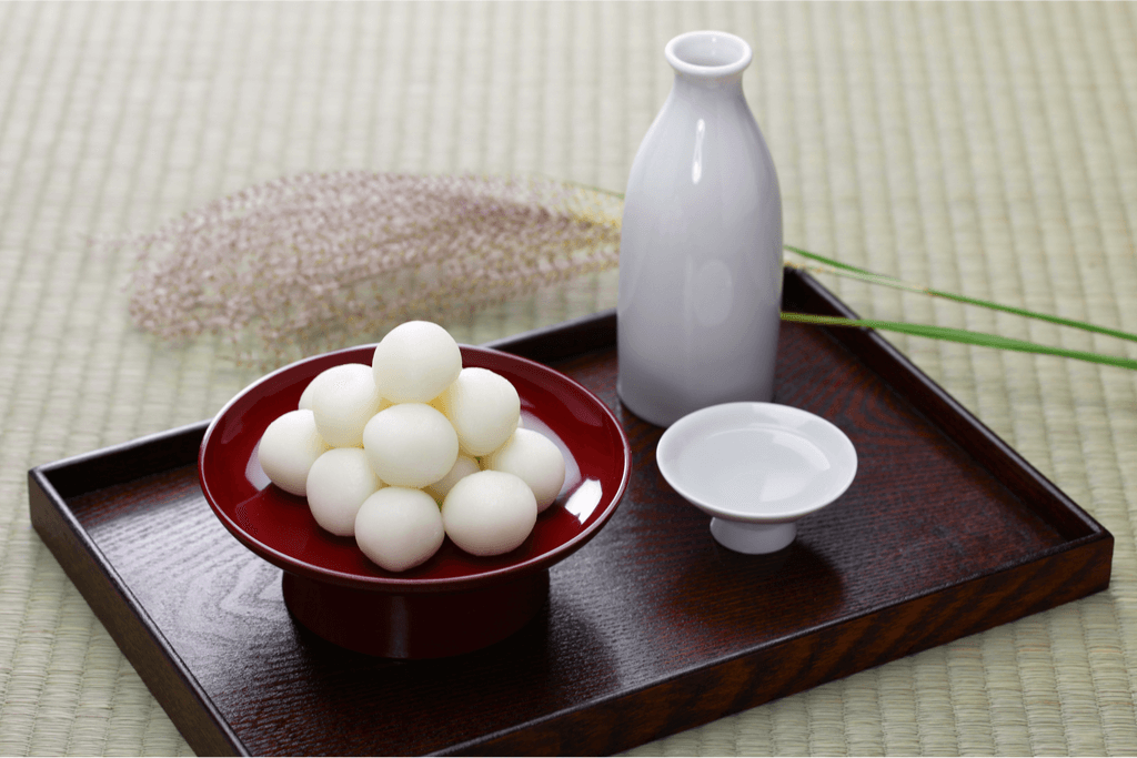 A picture of tsukimi dango and sake. The dango looks like little white balls, resembling little moons. It's one of many traditional tsukimi foods. 