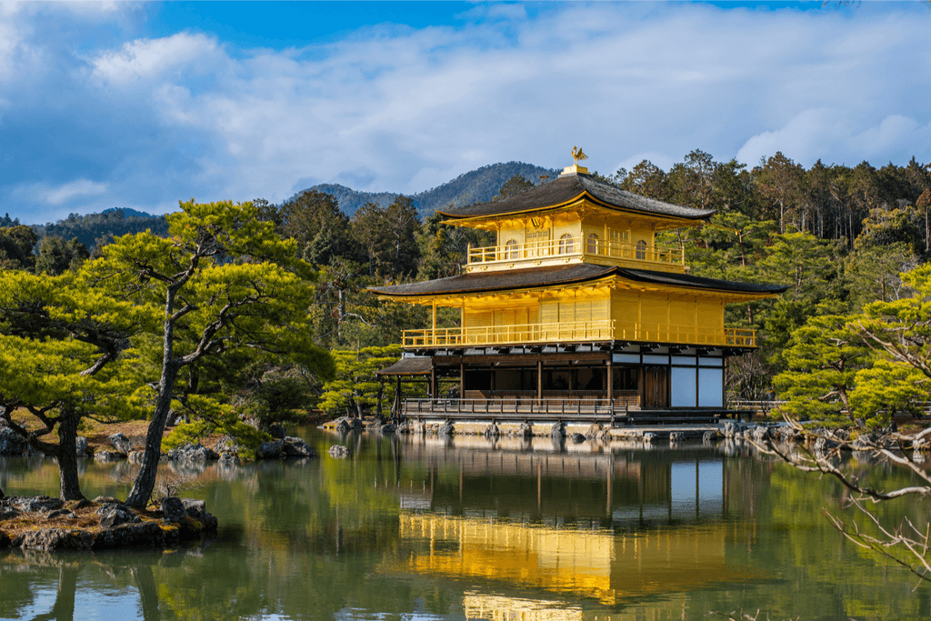 The Rokuon-ji Zen known as the golden temple is a Buddhist temple in Kyoto, Japan surrounded by green trees.