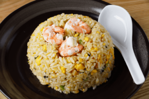 A plate of Japanese fried rice with shrimp on top.