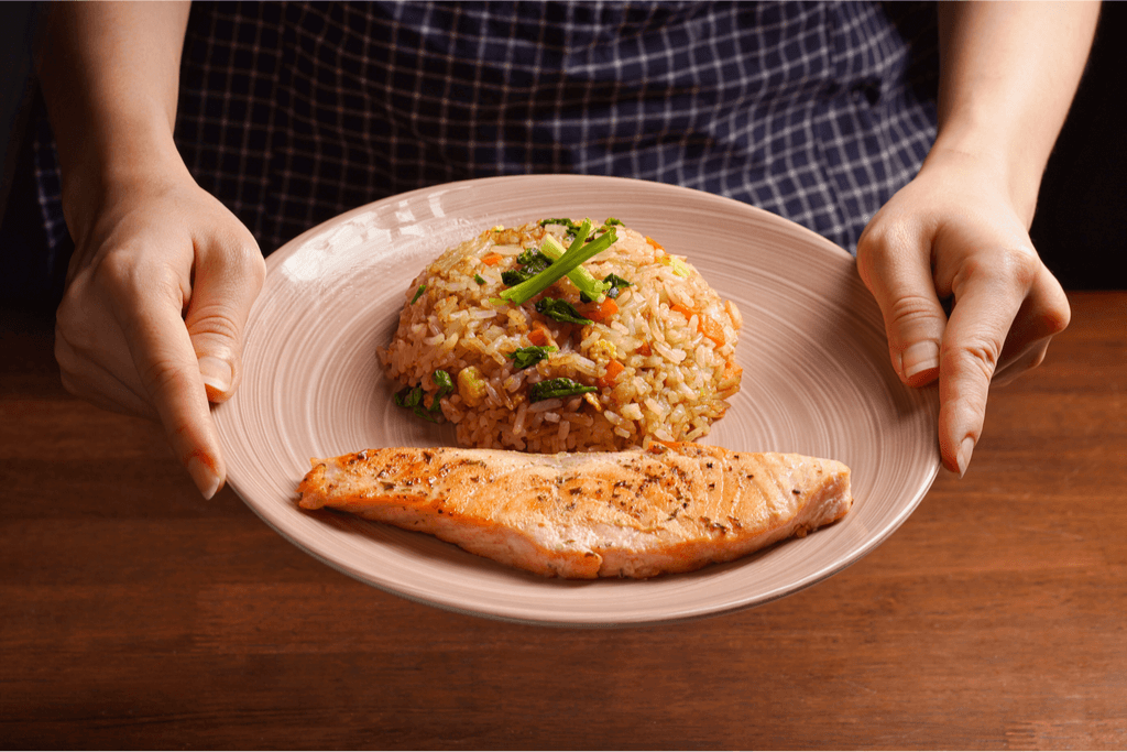 A plate of Japanese fried rice being served with a grilled salmon fillet.