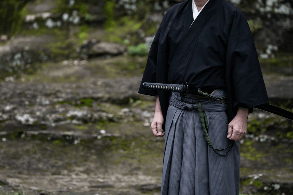 A man wearing black kimono and gray hakama pants, a form of traditional Japanese clothing.