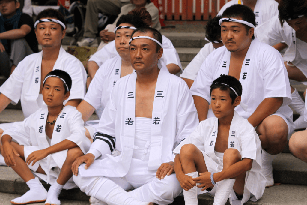 A group of men and boys wearing white happi jackets, at an Obon festival.
