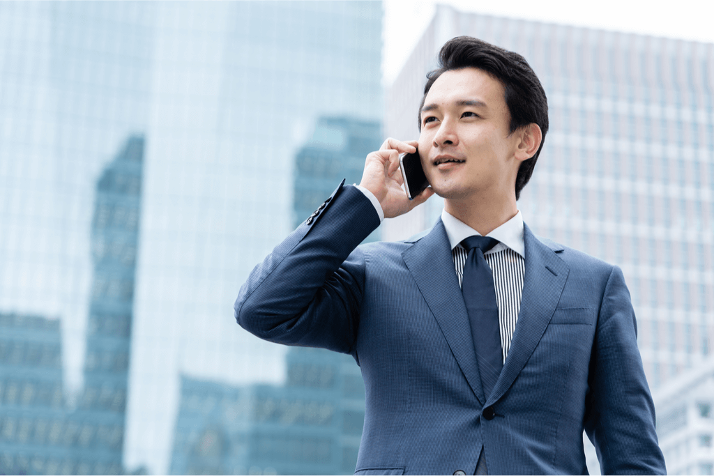 A Japanese man on his cellphone, wearing a business suit.