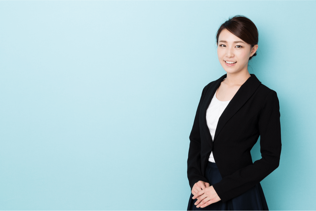 A Japanese woman in a business suit: white shirt, black blazer, black skirt. Wearing an appropriate suit is important for business etiquette in Japan.