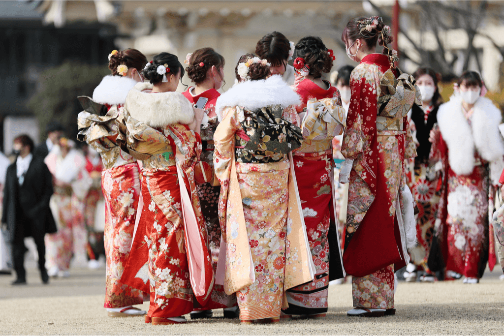 A group of young women dressed in ornate, long sleeved furisode kimono with fur collars. The furisode is a form of tradiitonal Japanese clothing.