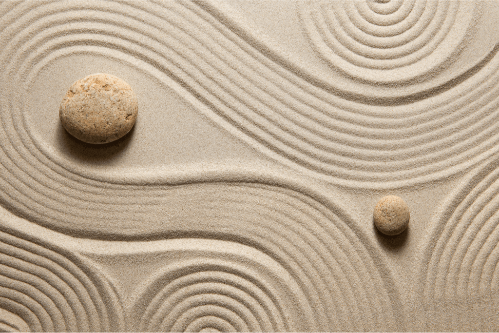 A photograph of beige stones on top of raked sand.