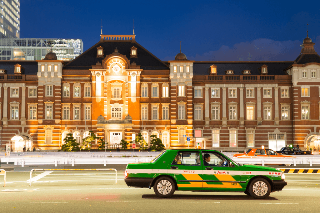 A green taxi outside of Tokyo Station.
