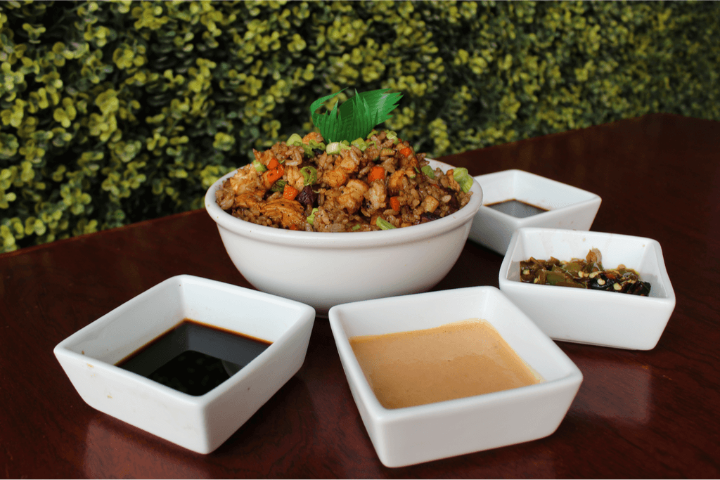 A bowl of yakimeshi rice surrounded by different dipping sauces.