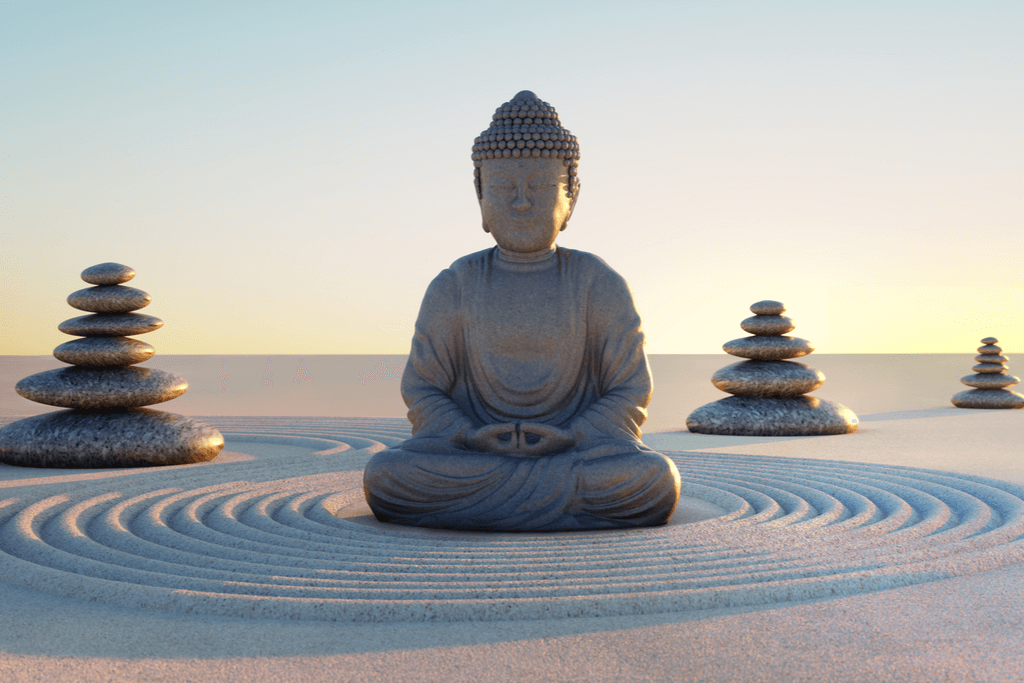 A photograph of a Buddha statue and stacks of grey rocks on gravel.