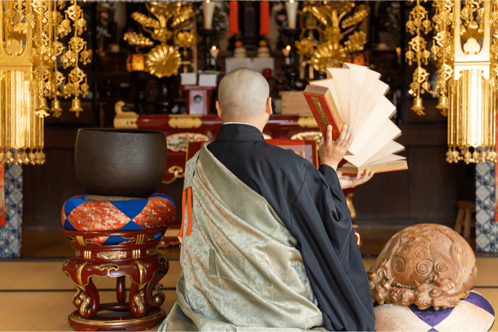 A Zen Buddhist monk with a prayer book, sitting at an altar.