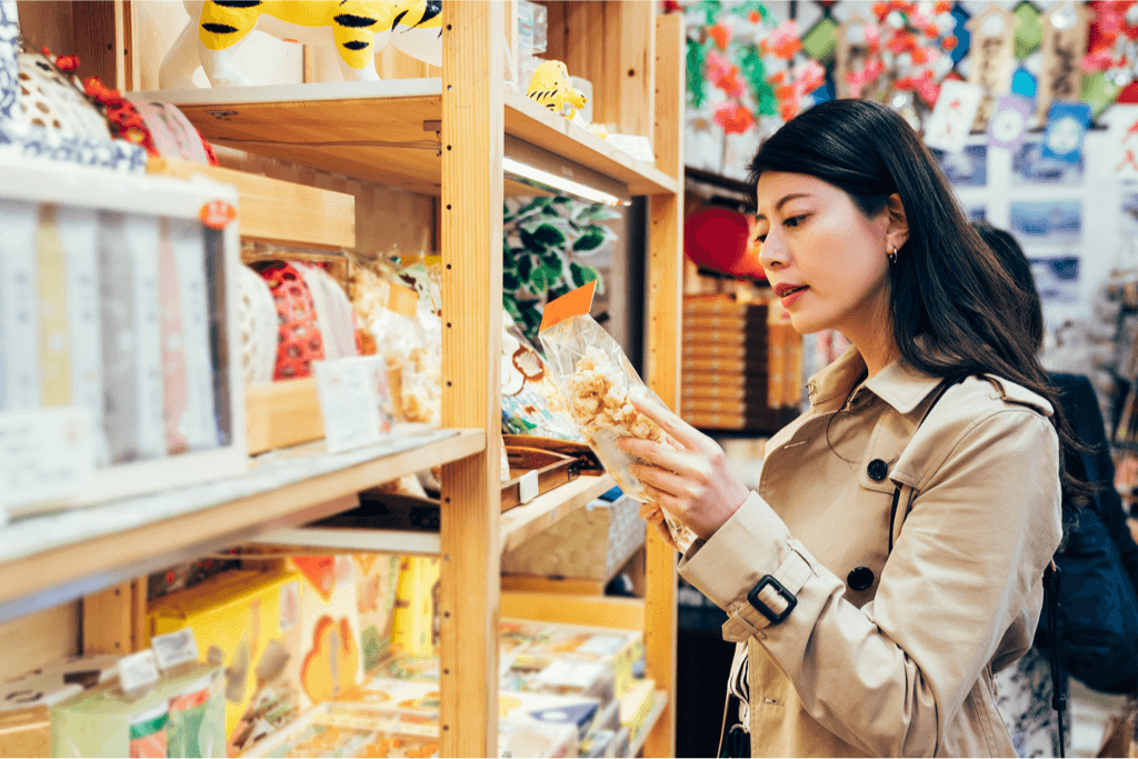 A young Japanese mother choosing a gift for a Japanese Housewarming Gift Giving snacks in a brightly shop in Japan 