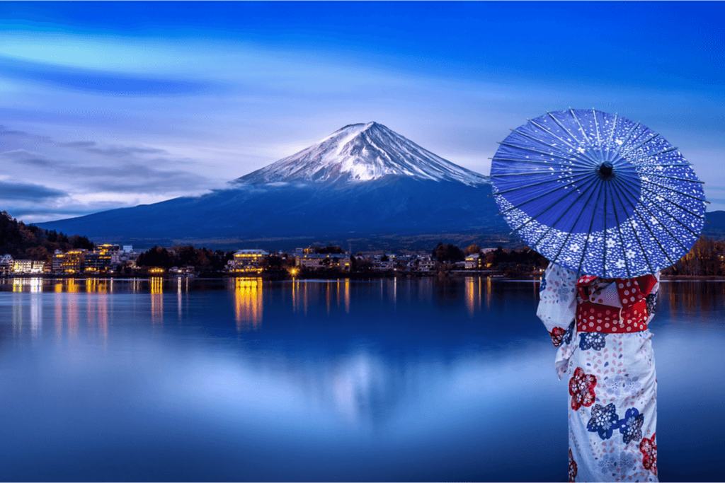 A woman in a kimono looking over at Mt Fuji one of many pythical monutains of Japan.