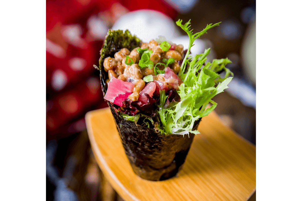 A pretty picture of hand rolled sushi made of green onion, salmon and natto.