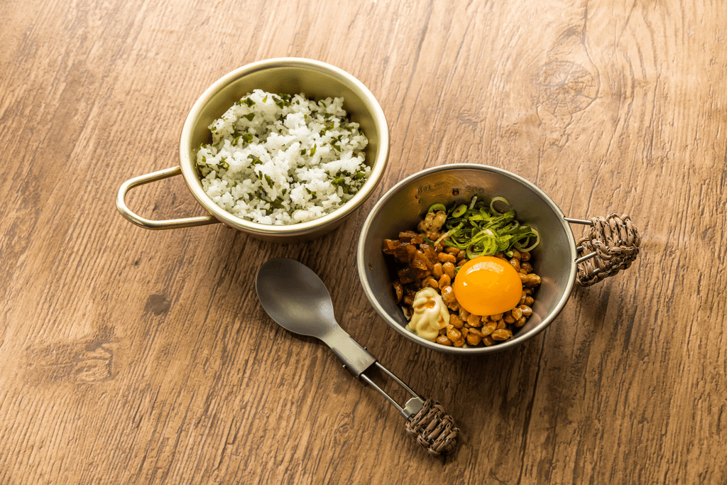 A meal consisting of lighytly seasoned rice and some toppings on the side, which include rice and egg.