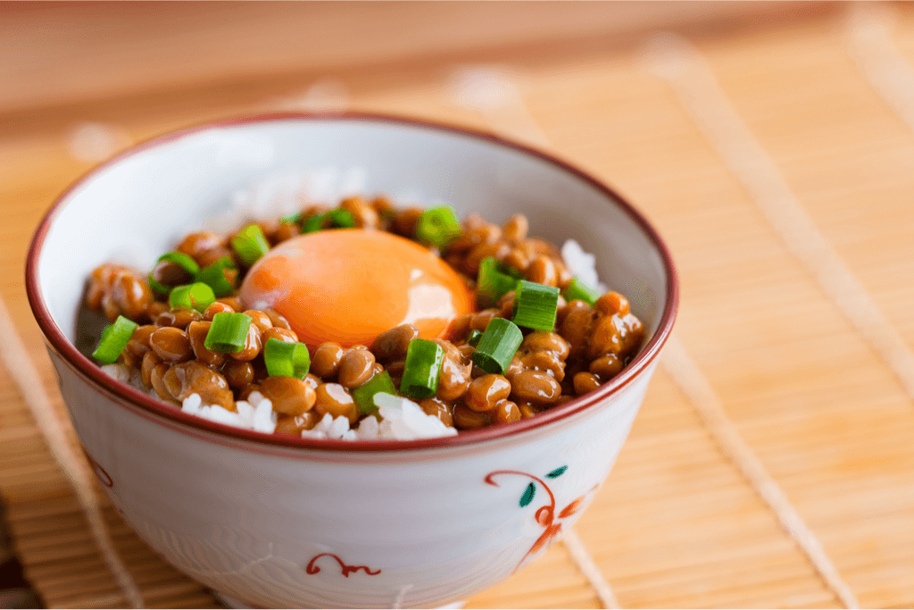 A bowl of natto rice with egg yolk and green onions.
