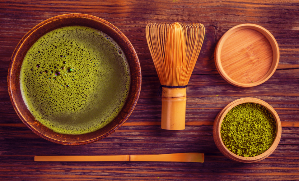 An assortment of matcha related Japanese products. There's matcha powder, a whisk and chopsticks.