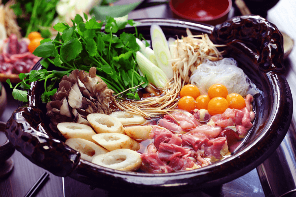 A simmering hot pot, or naabe, featuring meat, eggs, vegetables and tofu. This is one of many warm traditional Japanese foods.