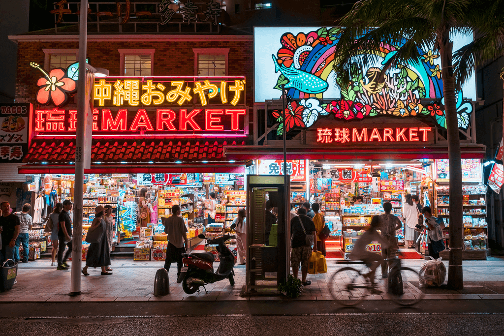 A nighttime shot of Kokusai Dori, a busy shopping street in Naha, Okinawa, Japan. It has many neon lights with a tropical vibe.