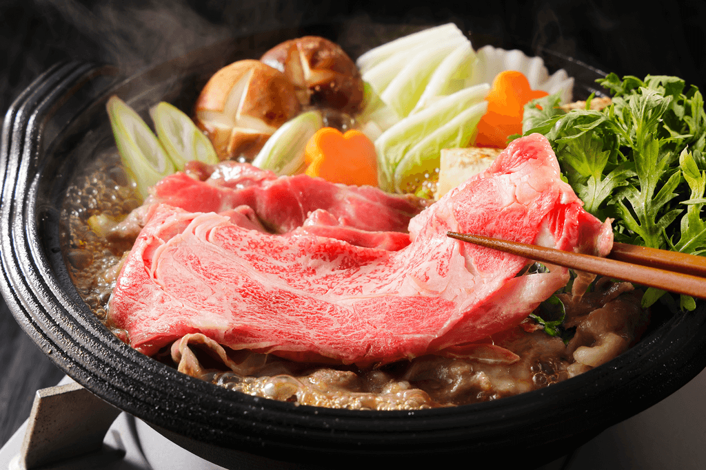 A simmering bowl of sukiyaki, featuring beef and vegetables.