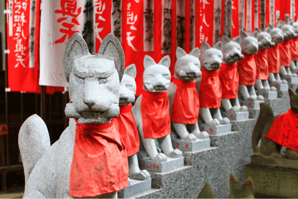 Rows and rows of gray stone foxes with red bibs in Aichi Prefecture.