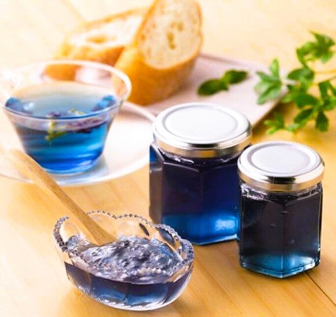 A shot of blue Japanese apple jam from Aomori. There are two jars of it, along with tea, and some separate jam in a glass dish.